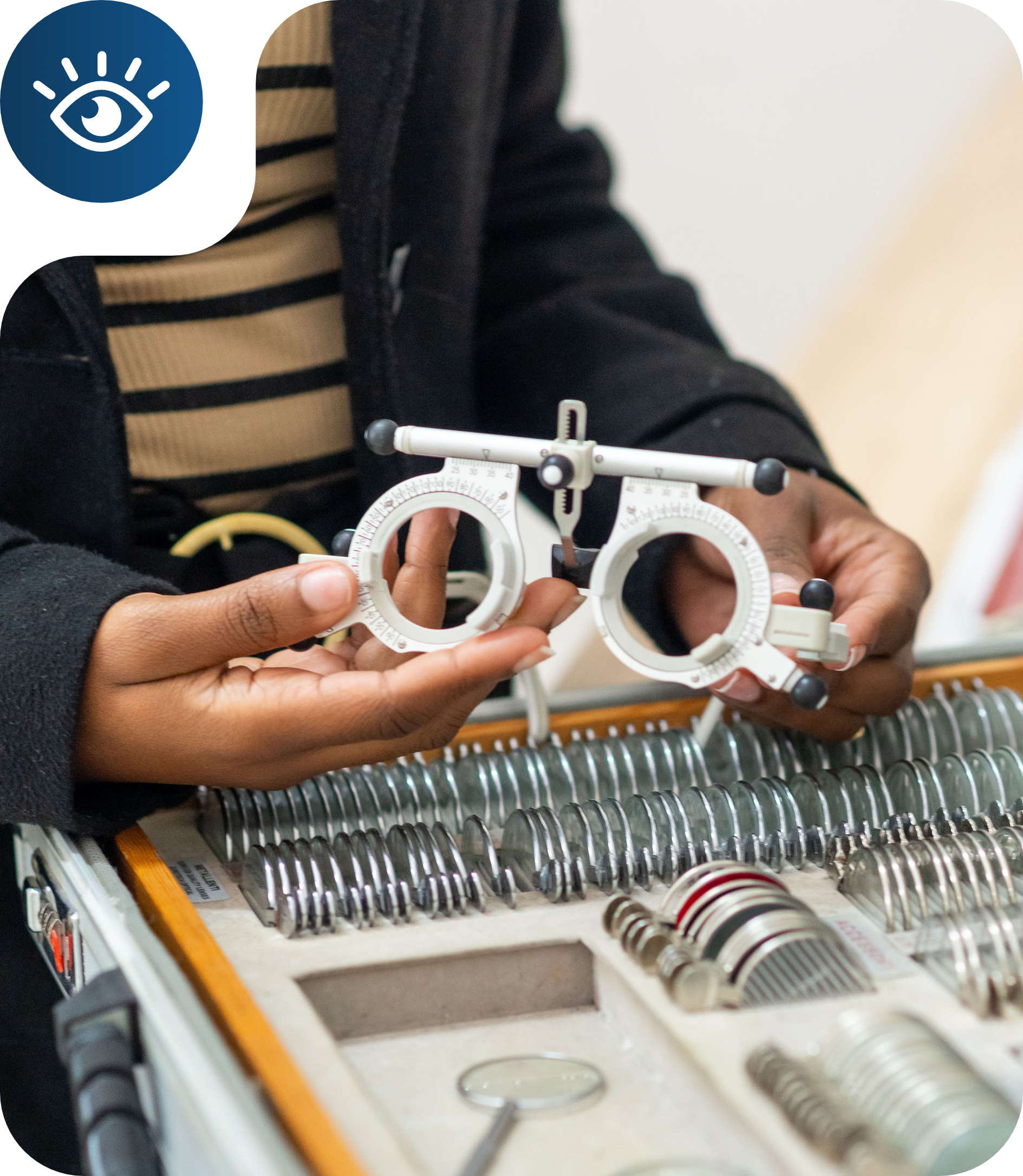 Person holding an optometry trial frame in front of a display case with various trial lenses.